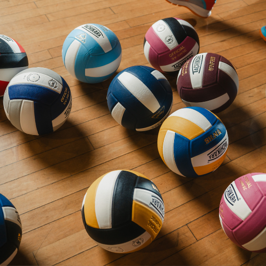 Colorful volleyballs on a wooden floor