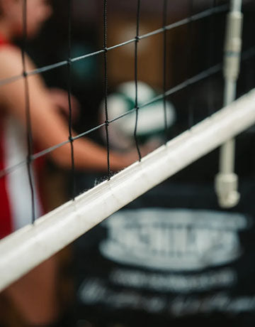 Close up of a volleyball net with players in the background