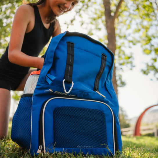 Blue backpack with visible brand logo on grassy ground