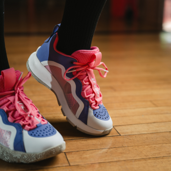 Pink and blue future volleyball shoes on a wooden floor